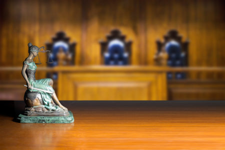 Lady justice and empty bench with judge chairs in courtroom